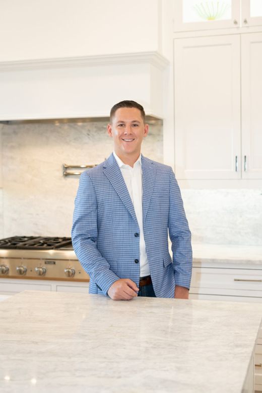 Chevy Goff in a white kitchen, leaning on a marble island